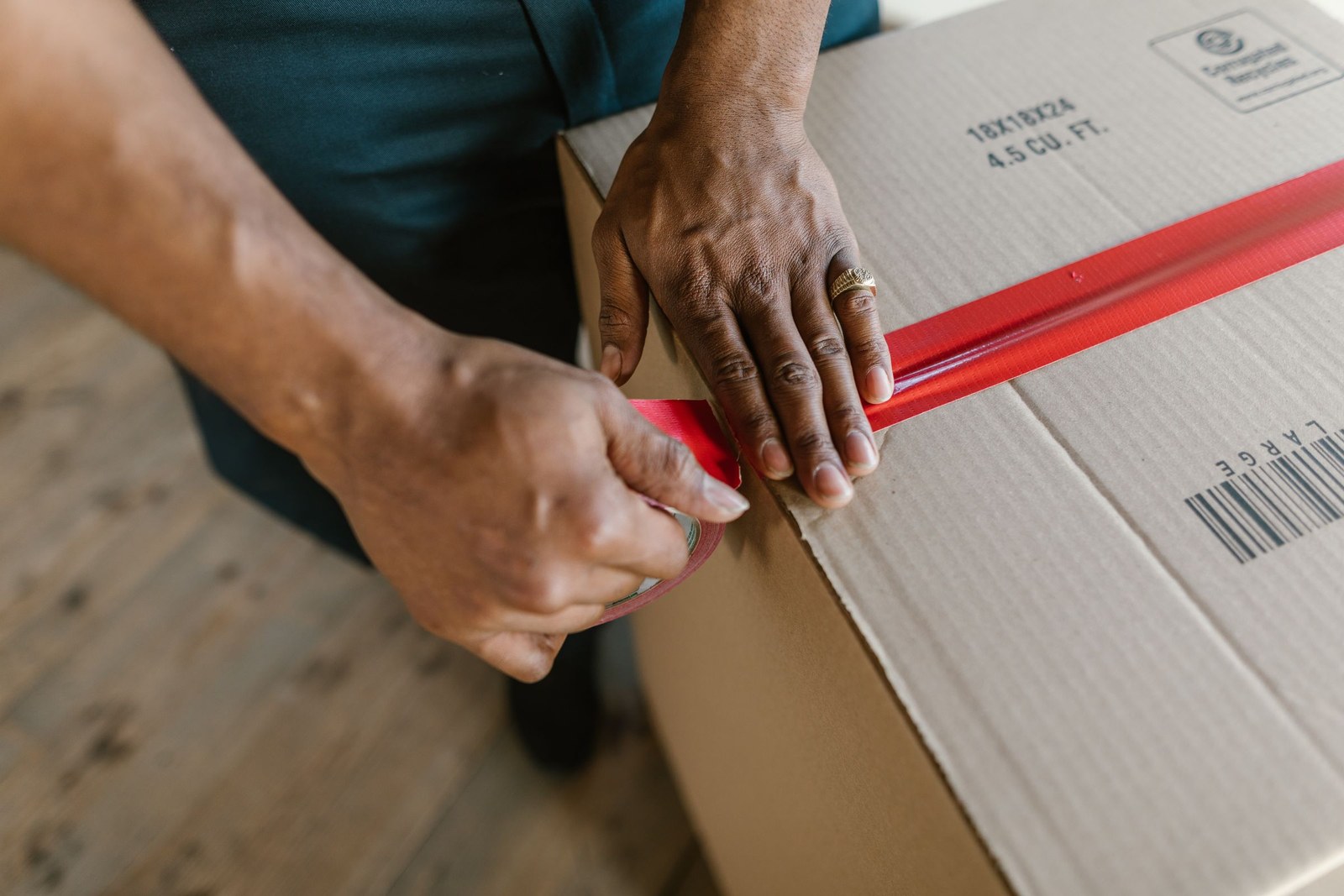 A cardboard box being sealed with packing tape